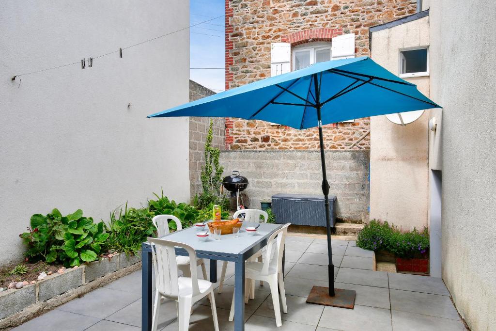 una mesa con una sombrilla azul en el patio en Escale a deux pas de la plage du Val Andre, en Pléneuf-Val-André