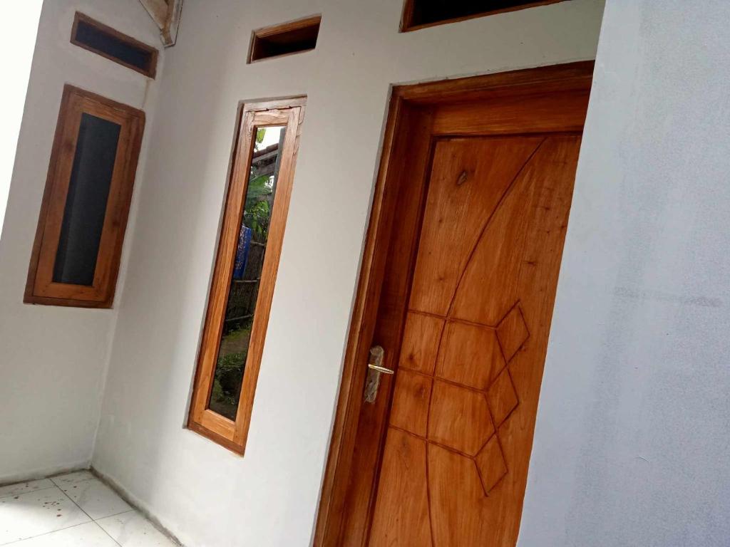 a wooden door in a white room with a window at 1Q rural in Sukabumi