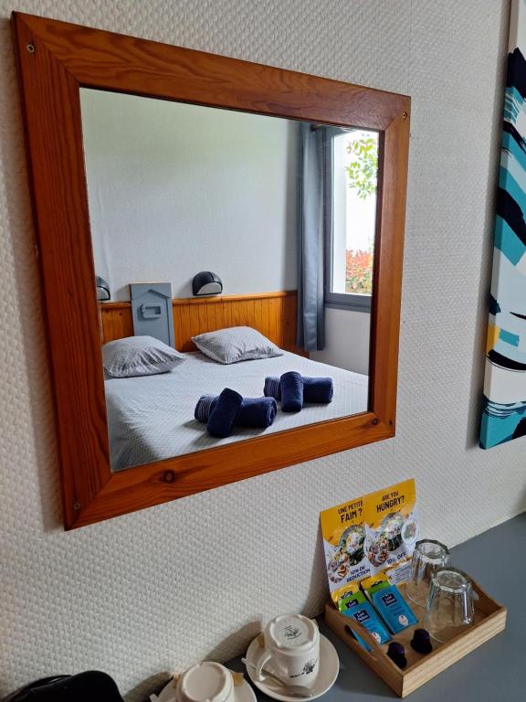 梅里尼亞克的住宿－Escale Kennedy，卧室配有一张壁挂镜子的床