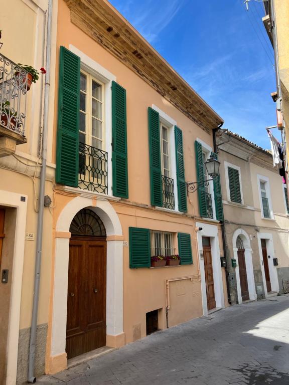 a building with green shutters on a street at Charmante vakantiewoning 'Casa Di Tonno' in Loreto Aprutino