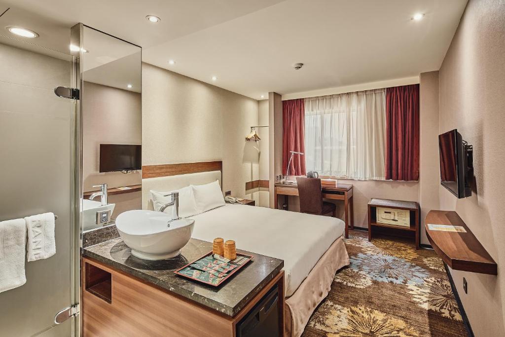 台北市にあるオレンジ ホテル リンセン タイペイの大きなベッドとバスルームが備わるホテルルームです。