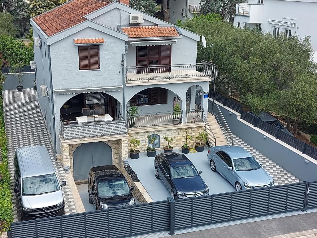 drie auto's geparkeerd op een parkeerplaats voor een huis bij Villa M & D in Sveti Filip i Jakov