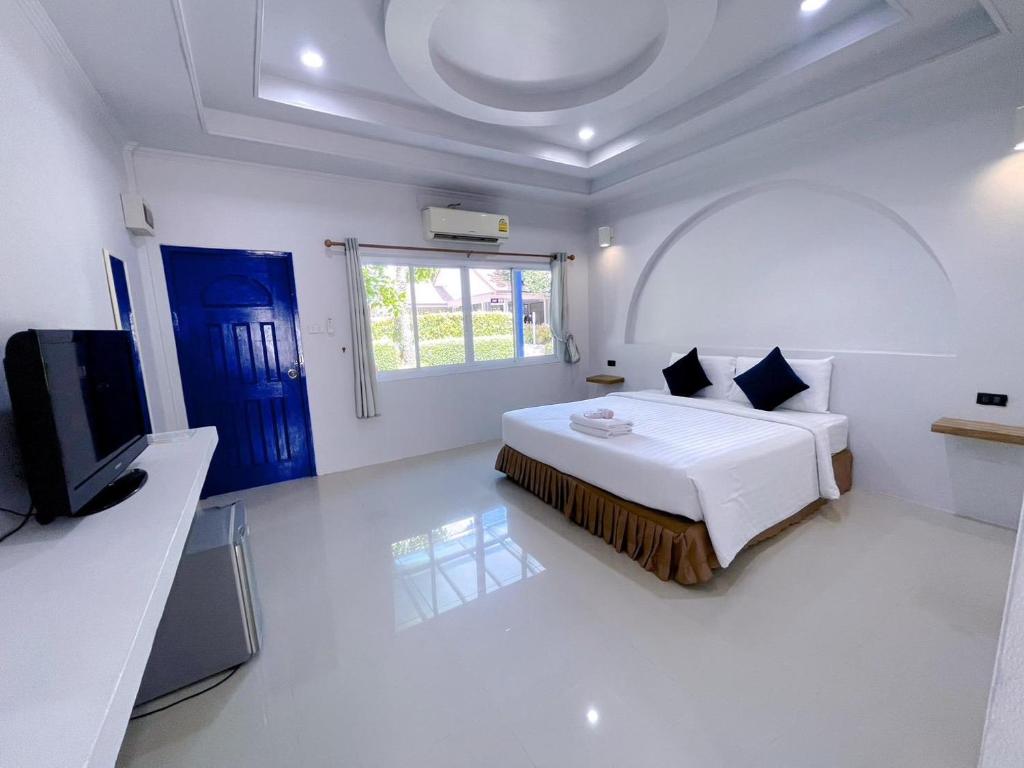 Cette chambre blanche dispose d'un lit et d'une télévision. dans l'établissement Sky View Resort Buriram, à Buriram