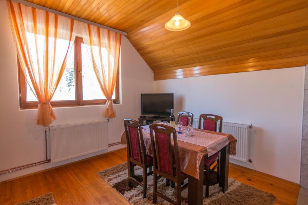 Kod Goluba na Tari في Šljivovica: غرفة طعام مع طاولة مع كراسي وتلفزيون