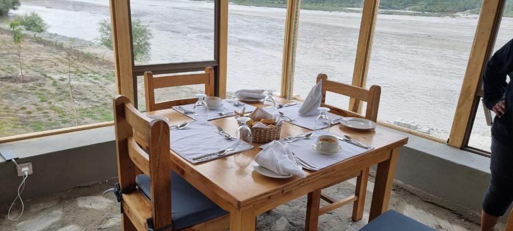 einen Tisch mit Tellern und Servietten mit Blick auf das Wasser in der Unterkunft Guzel Hotel in Shigar