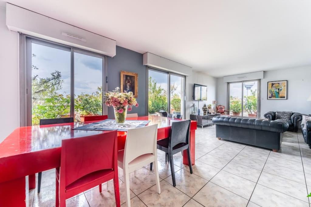 une salle à manger avec une table et des chaises rouges dans l'établissement Appartement avec terrasse a 5 min de Paris, aux Lilas