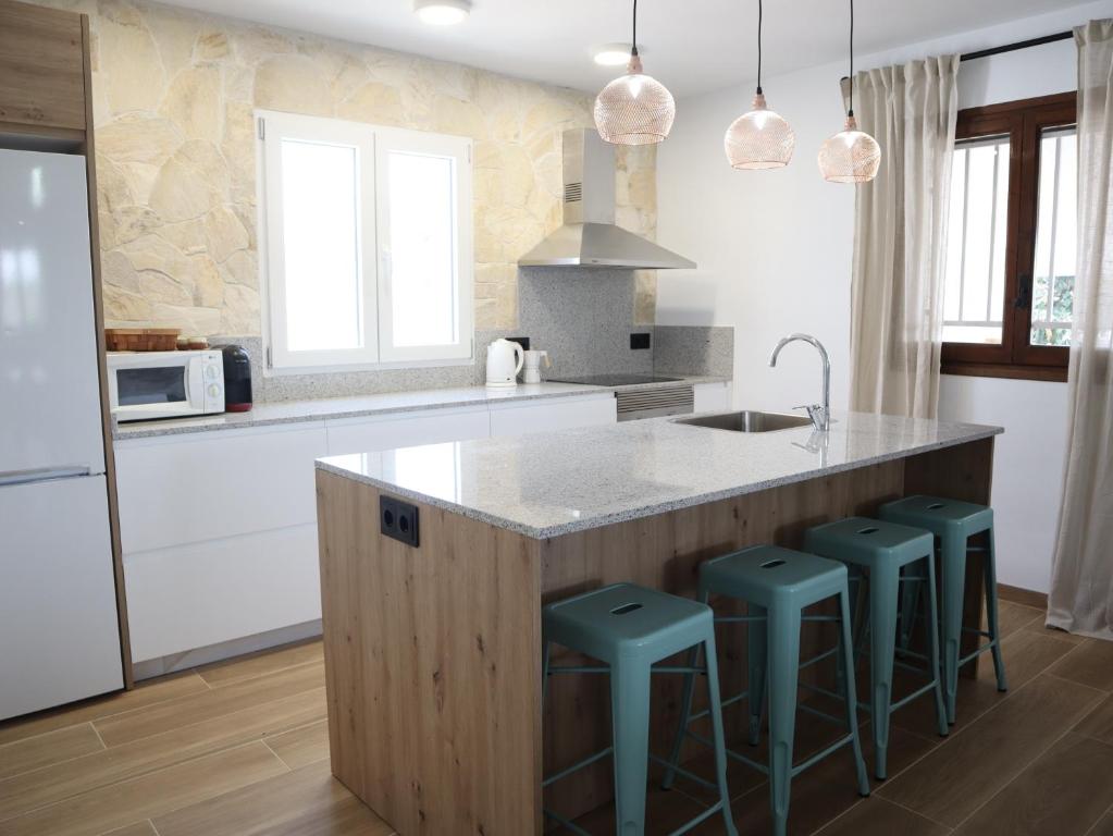 a kitchen with a large island with green bar stools at Nina´s Paradise in L'Ampolla