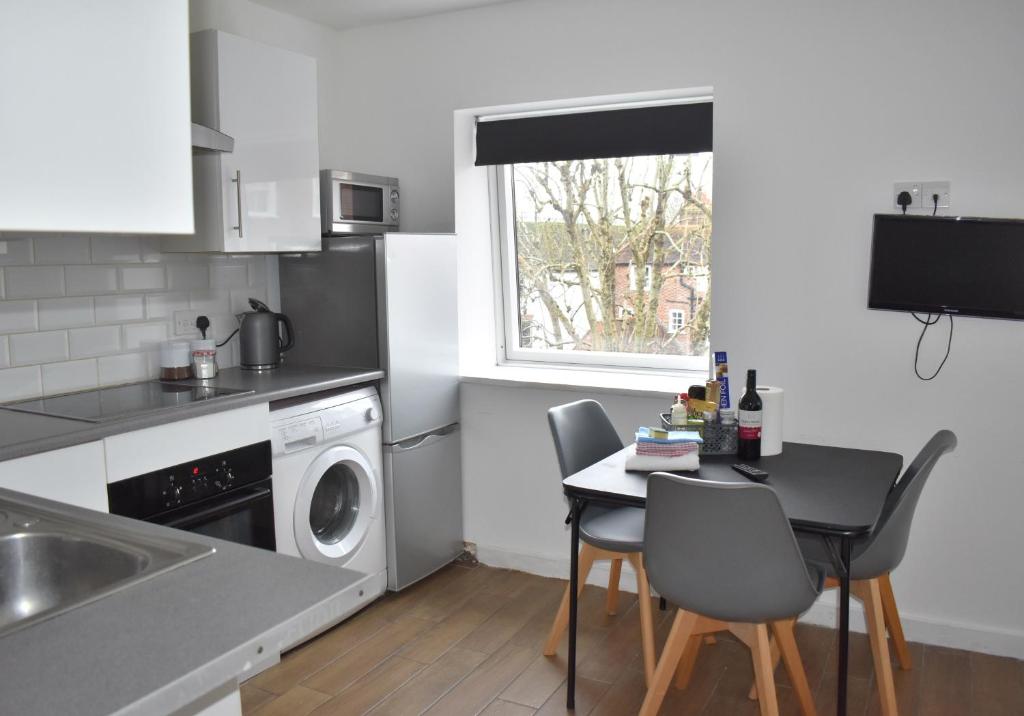 a kitchen with a table and a washing machine at Chichester Retreat - Quiet City Centre Apartment in Chichester