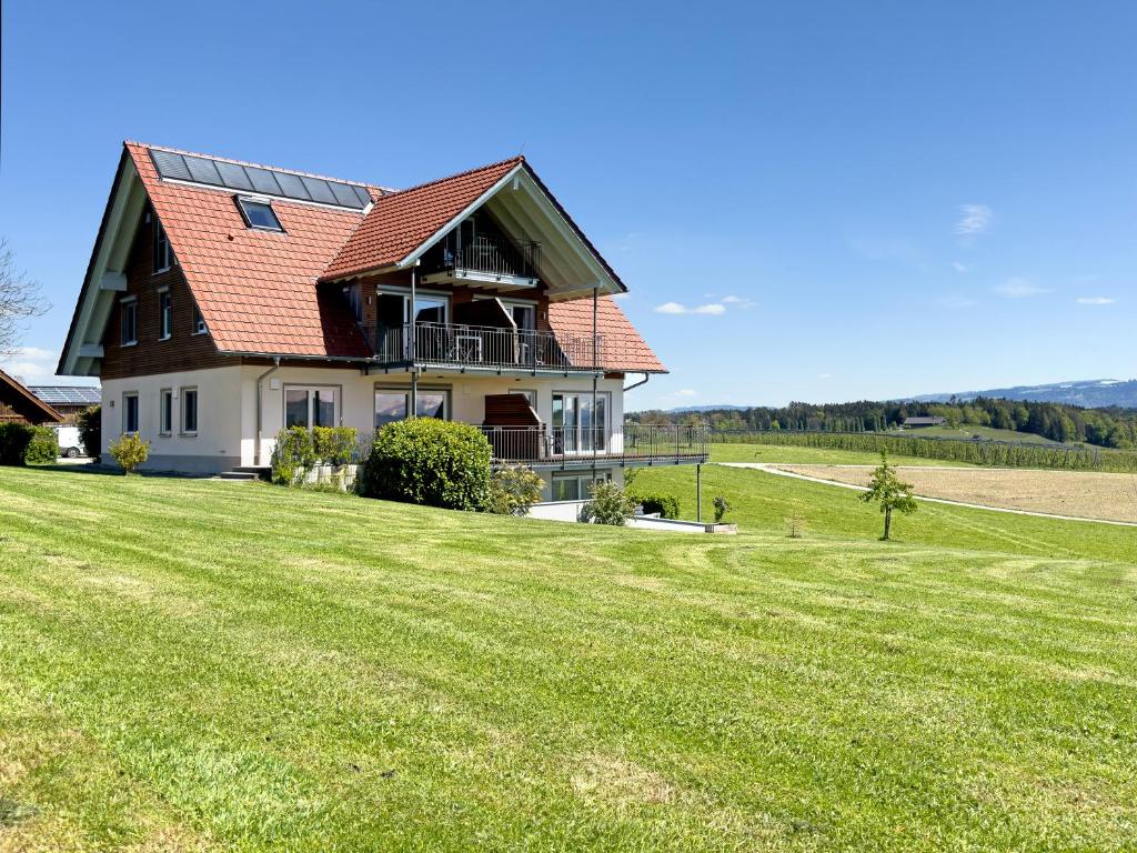 dom z czerwonym dachem na zielonym polu w obiekcie Ferienhof Lang w mieście Kressbronn am Bodensee