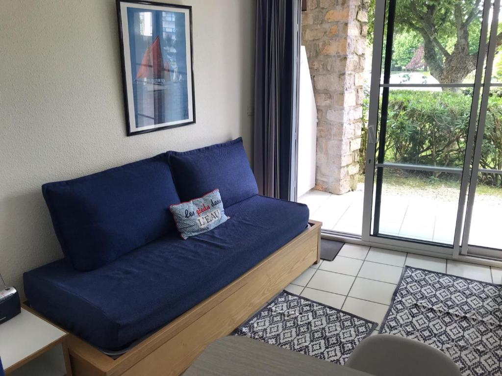 - un canapé bleu dans le salon doté d'une fenêtre dans l'établissement Appartement bord de mer, à Arzon