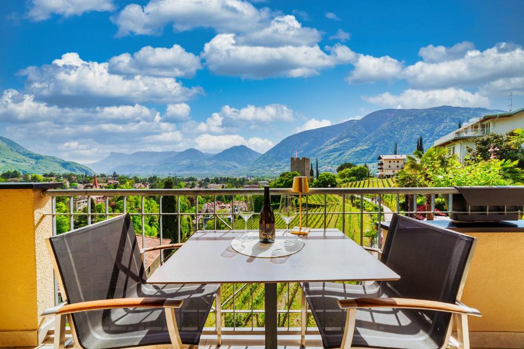 een tafel en stoelen op een balkon met uitzicht op de bergen bij Levita Living Anima in Merano