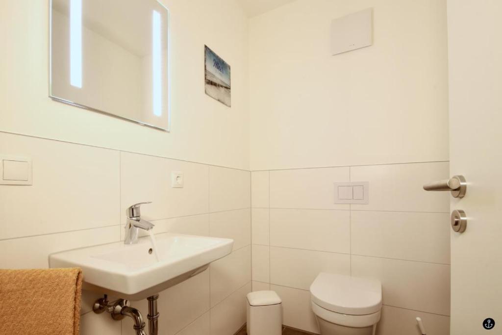 ein weißes Bad mit einem Waschbecken und einem WC in der Unterkunft Neue Liebe Haffkrug 4 in Haffkrug