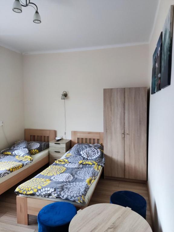 twee bedden in een kamer met twee blauwe stoelen bij Kwatery Rydz in Częstochowa