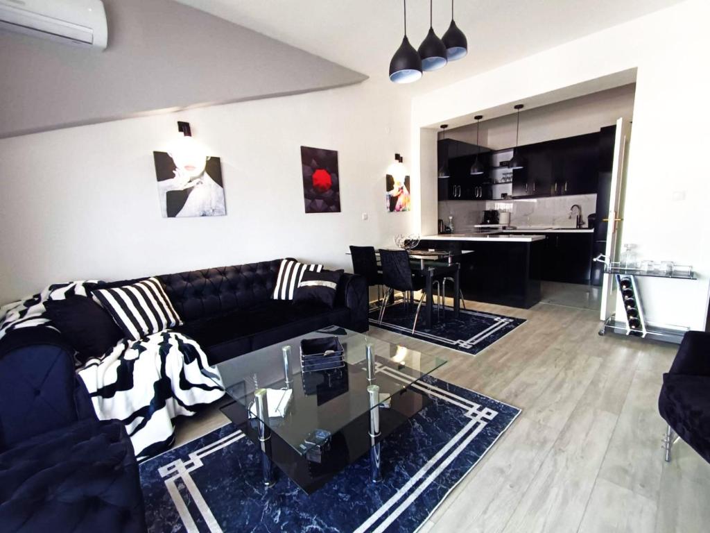 een woonkamer met een zwarte bank en een glazen tafel bij Dostin's Loft 75 in Ohrid