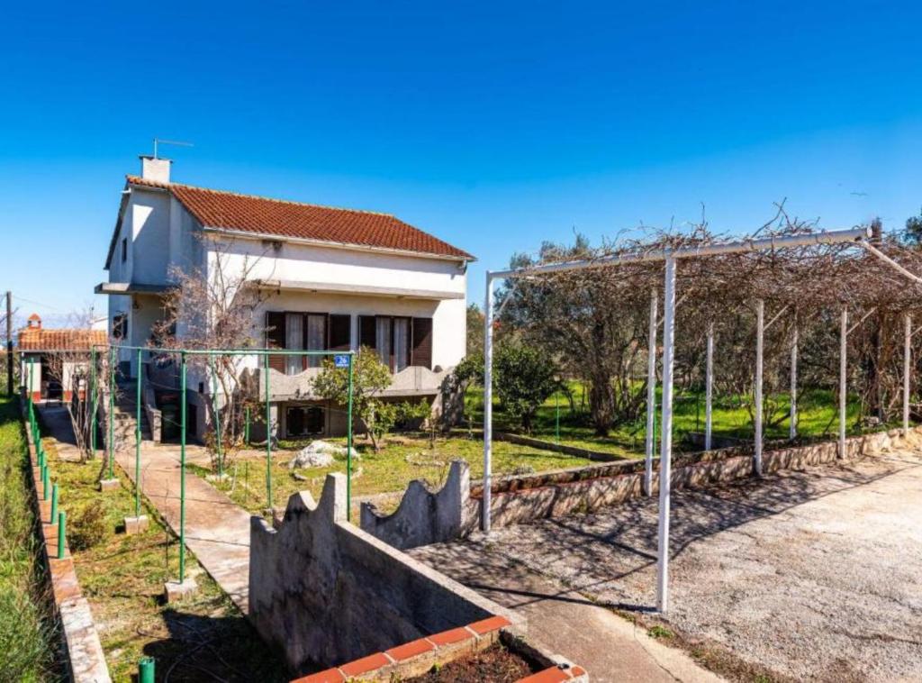 a fence in front of a building and a house at Apartment Serđa in Ugljan