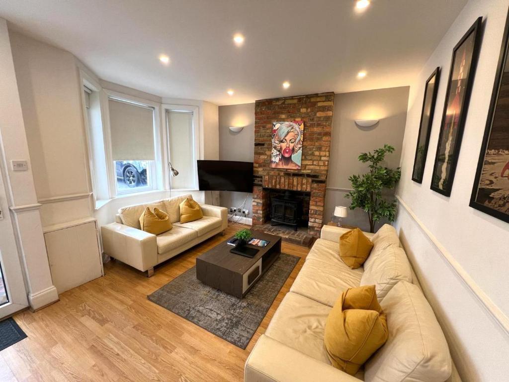 a living room with a couch and a fireplace at Great 4 bedroom House - Great Location - Garden - Parking - Fast WiFi - Smart TV - Newly decorated - sleeps up to 8! Only 10 mins drive to Sandbanks Beach! Close to Poole & Bournemouth in Parkstone