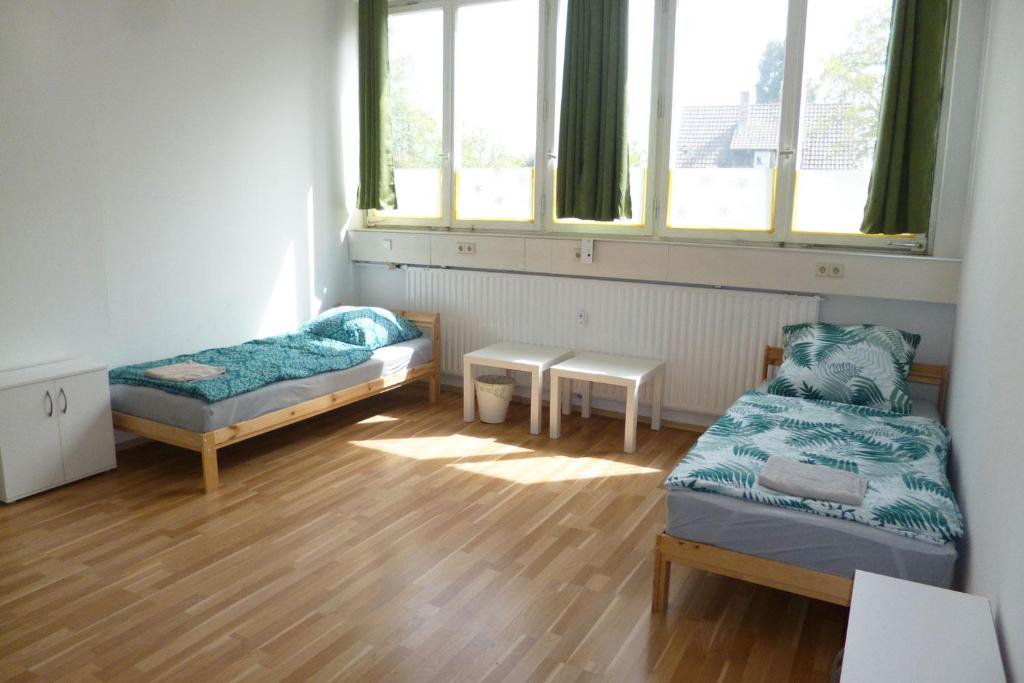 Cette chambre comprend 2 lits, une table et des fenêtres. dans l'établissement Nice Apartment in Vöhringen, à Vöhringen