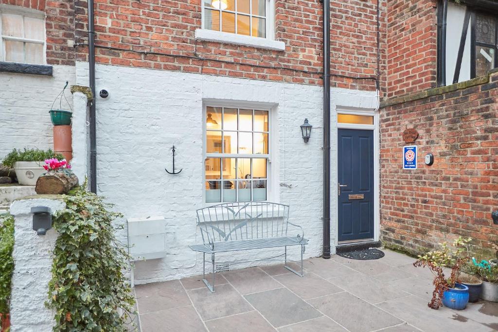 a bench sitting outside of a brick building with a blue door at Seashell Cottage in Whitby