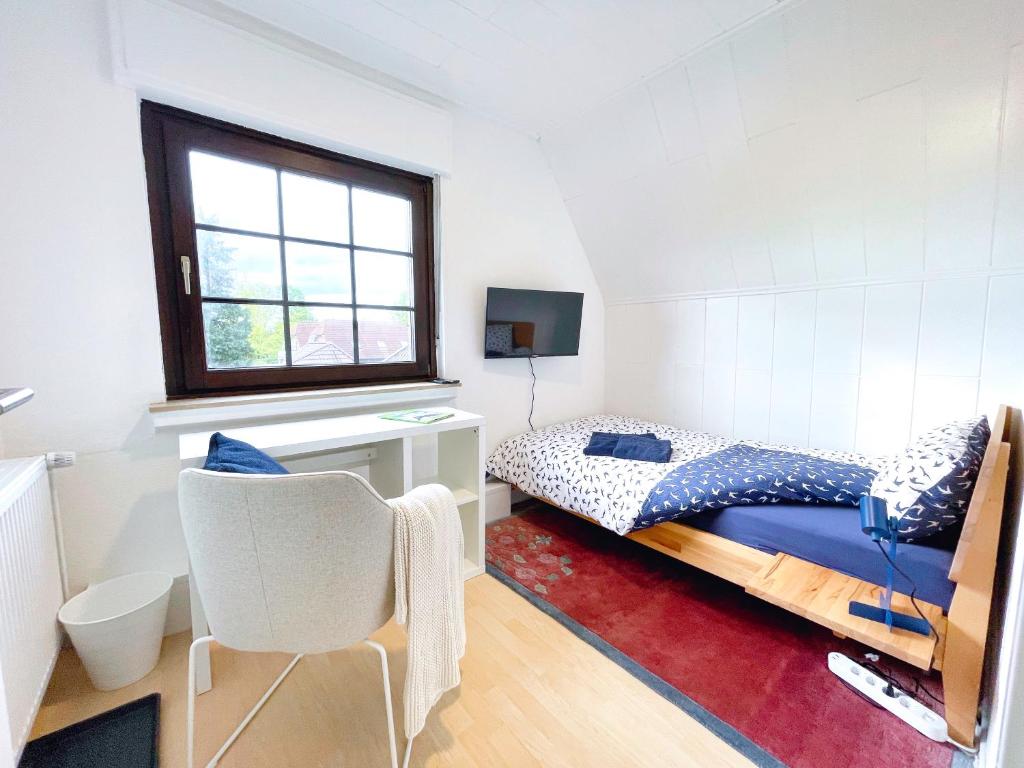 1 dormitorio con cama, escritorio y ventana en Monteurwohnung, 6 Einzelzimmer, 2024 renoviert, Smart TV, Garten, neue Bäder en Ibbenbüren