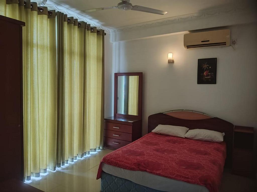 Schlafzimmer mit einem Bett und einem Fenster mit Vorhängen in der Unterkunft Beach view luxury apartment in Karagampitiya