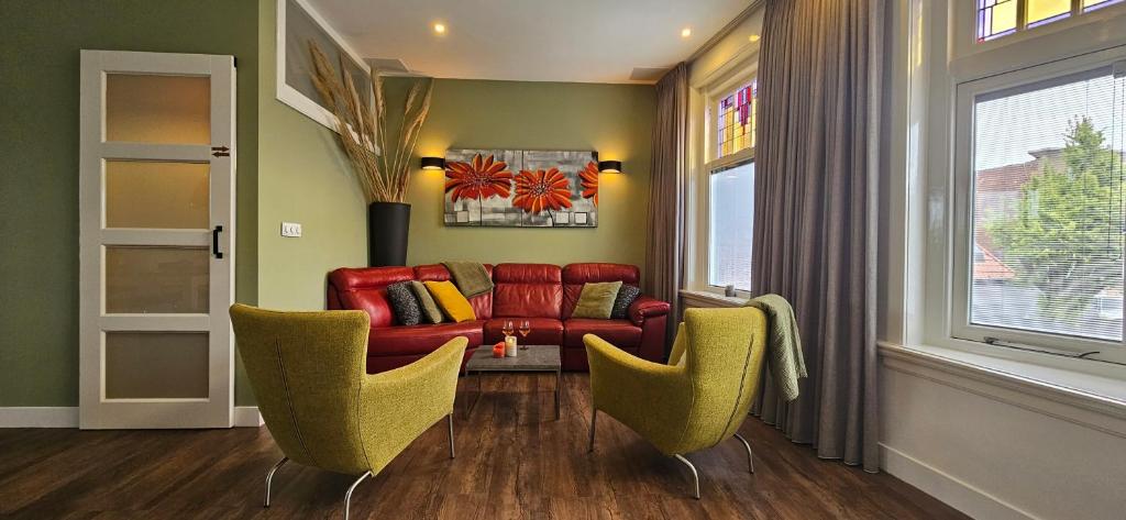 a living room with a red couch and two chairs at Heerehuys Lisse in Lisse