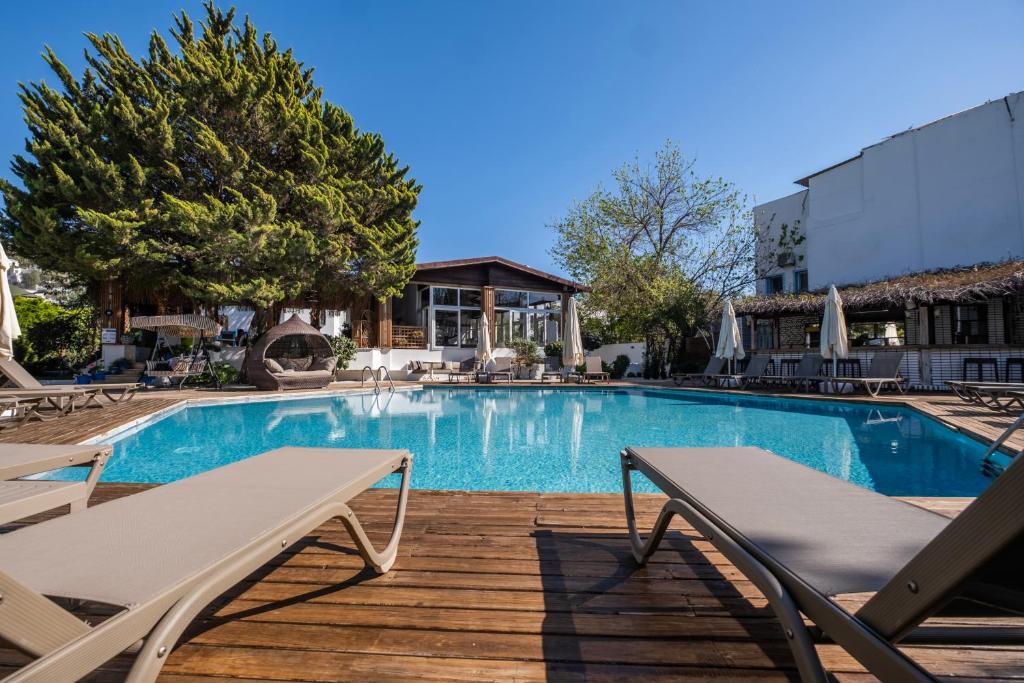 a swimming pool with two lounge chairs on a wooden deck at Costa Bodrum City in Bodrum City