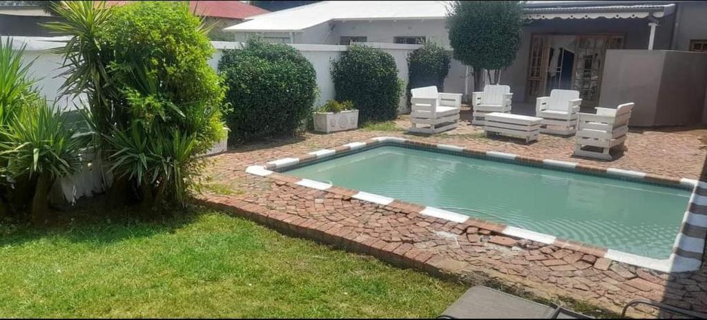 una piscina con 2 sillas de césped en WAMPEX GUEST HOUSE POTCHESTROOM, en Potchefstroom