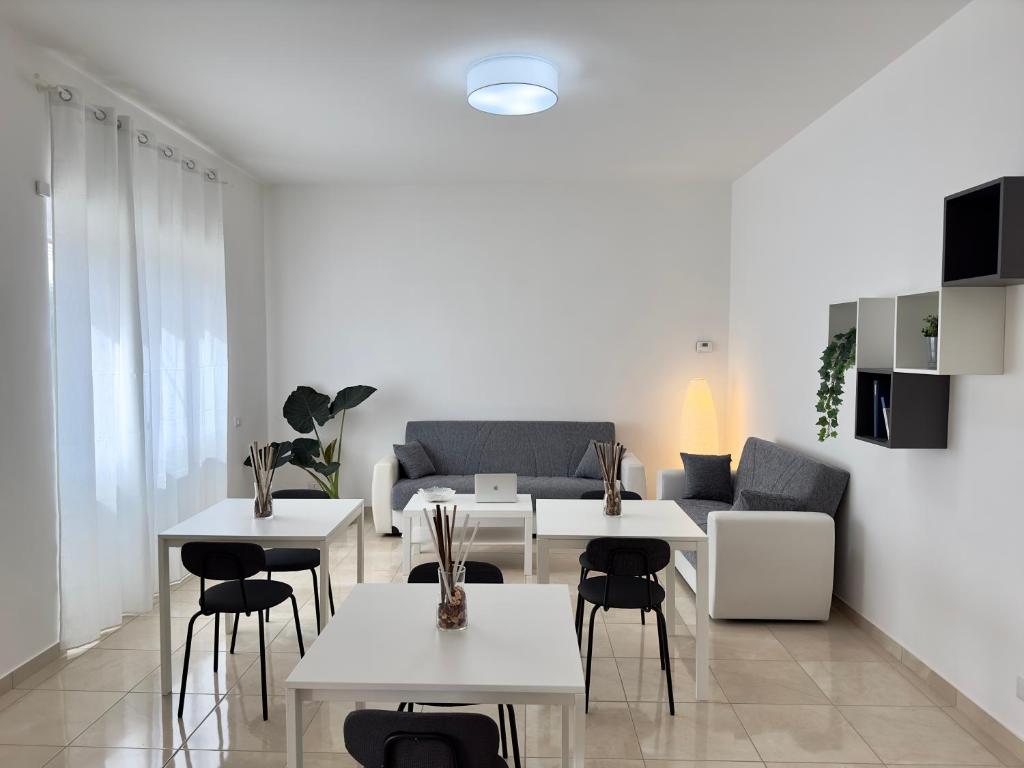 ein Wohnzimmer mit weißen Tischen und einem Sofa in der Unterkunft 110 mq piano terra- Parcheggio privato-Giardino in Velletri