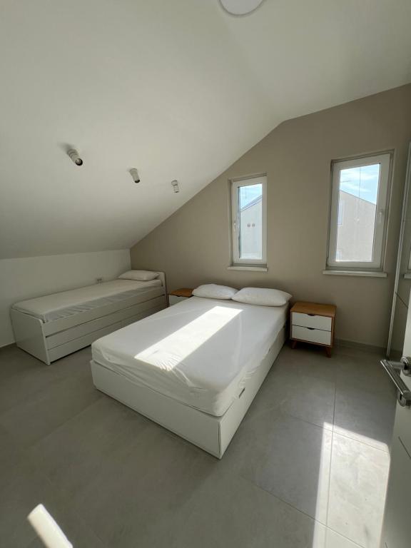 um quarto branco com 2 camas e 2 janelas em Penthouse SKY DELUXE em Novalja