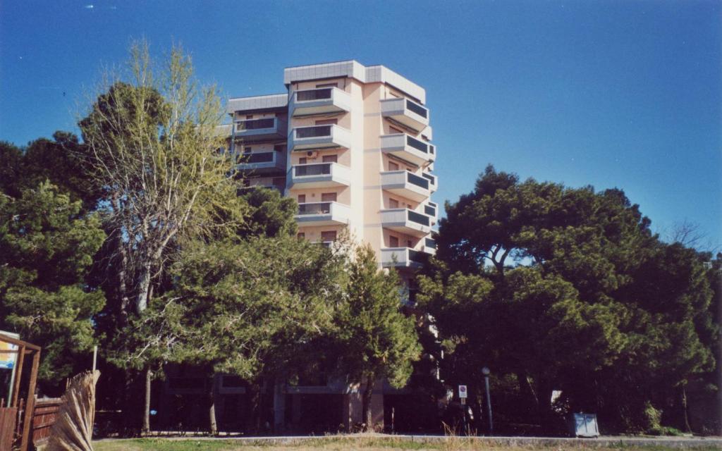 een hoog appartementencomplex met bomen ervoor bij Appartamento Miramar in Grado-Pineta