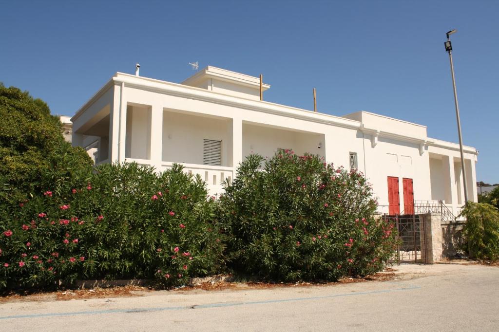uma casa branca com portas vermelhas e alguns arbustos em Casa Bianca 4 camere 4 bagni in villa con giardino e terrazza em Santa Cesarea Terme