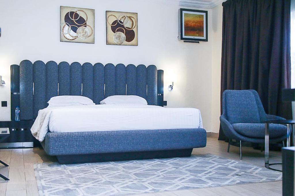 a bedroom with a large bed and a blue chair at Summerset Continental Hotel Maitama in Abuja