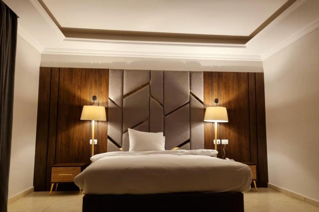 a bedroom with a large bed with two lamps at Grand Plaza 6 Octobar in Qaryat ash Shamālī