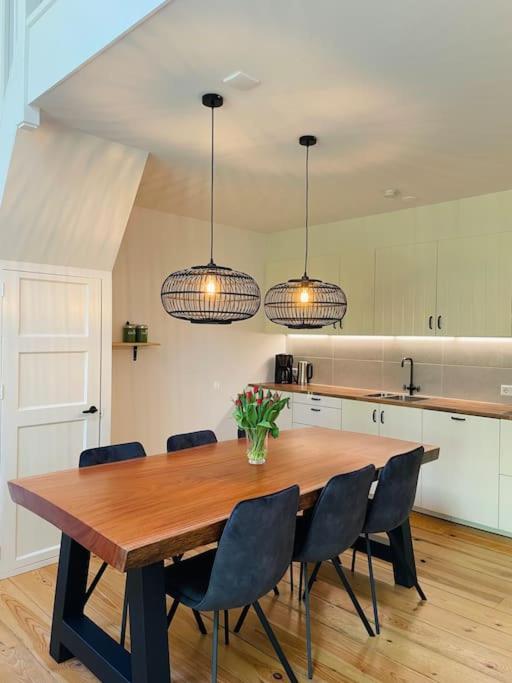 Appartement Boothuis في سنيك: مطبخ مع طاولة خشبية مع كراسي واضاءات