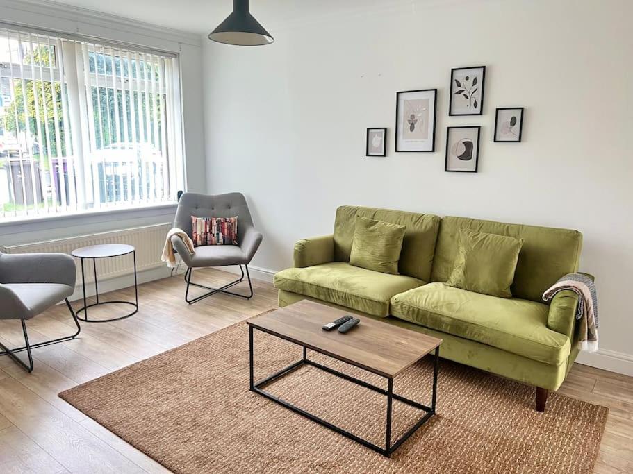 een woonkamer met een groene bank en een tafel bij Ideal 3 Bed Home In Glasgow City With Free Parking in Glasgow
