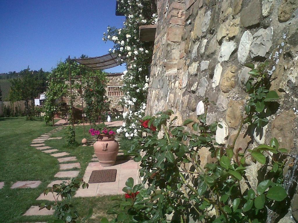 un muro di pietra con un vaso di fiori su un sentiero di La Rocca Chianti Hospitality a Tavarnelle in Val di Pesa