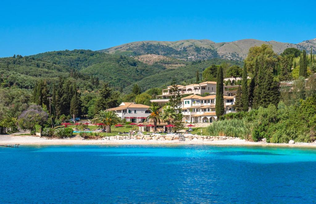 a resort on a beach with mountains in the background at Bella Mare Hotel in Kassiopi
