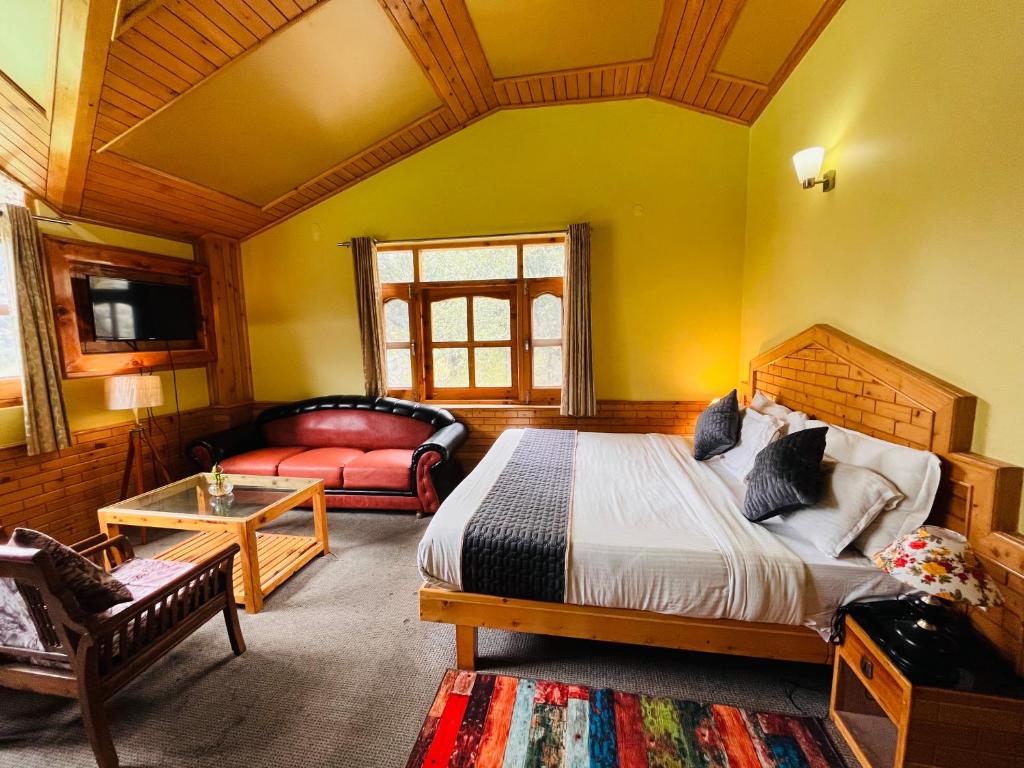 a bedroom with a bed and a couch in a room at Snow Clad Riverview Hotel & Resort, Manali in Manāli