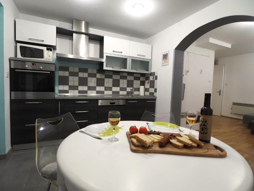 einen Tisch mit einem Tablett mit Essen und zwei Gläsern Wein in der Unterkunft Apartment with garden in Barbariga in Barbariga