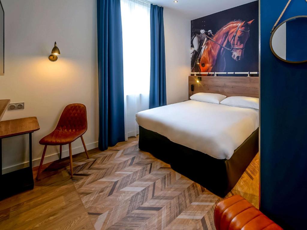 Habitación de hotel con cama y silla en ibis Styles Saumur Gare Centre, en Saumur