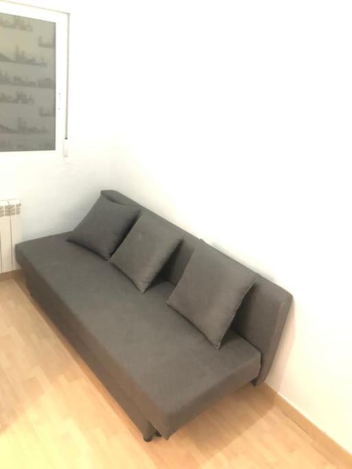 un sofá en una habitación con 2 almohadas en Estudio en calle Canarias, zona Atocha - Delicias, en Madrid