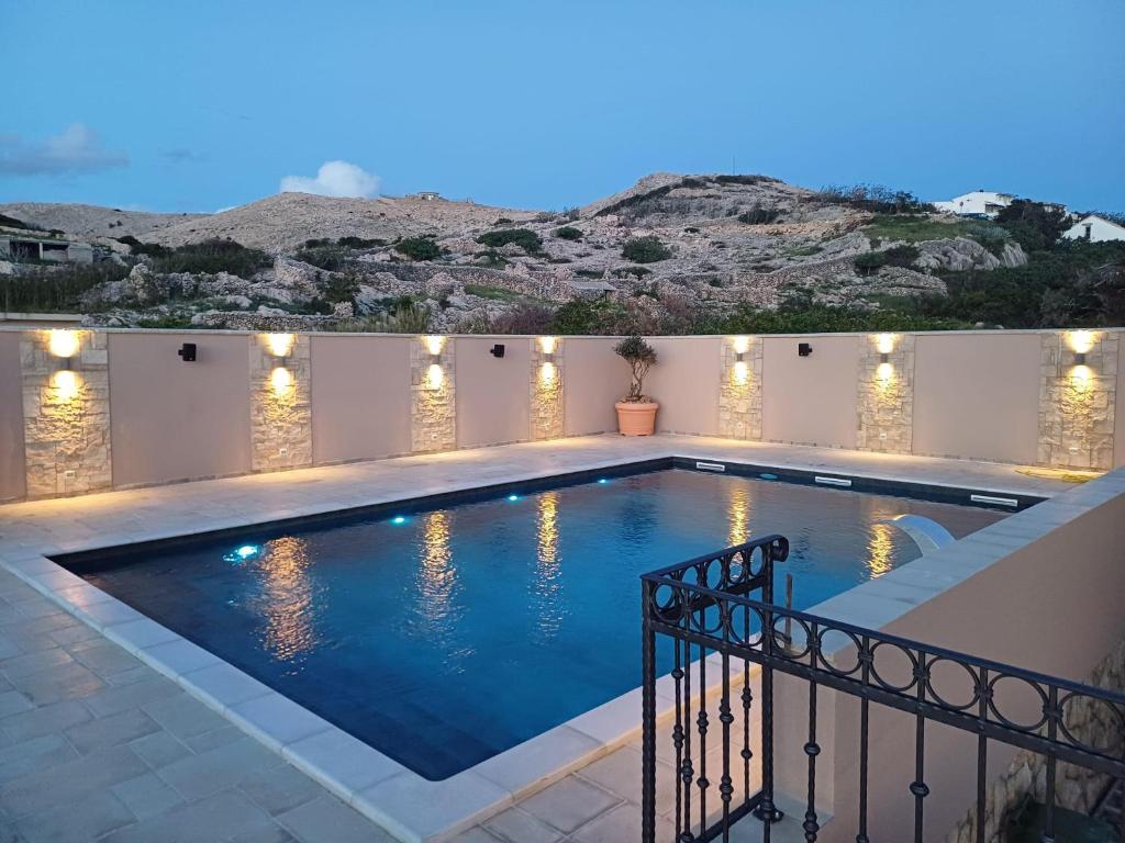 a swimming pool with lights on the side of a house at Bed & Breakfast Marta & Tona in Novalja