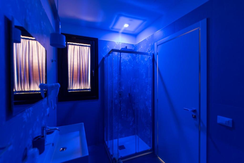 a blue bathroom with a shower and a sink at Room & Breakfast Aloe in San Vito lo Capo