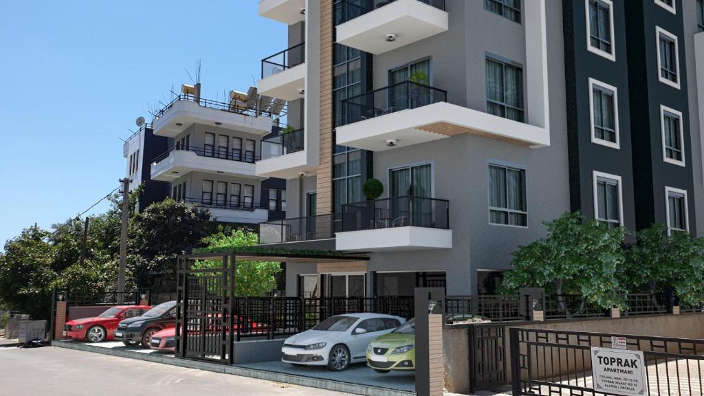 a building with cars parked in a parking lot at CZG SUİTE PREMİNYUM SİTESİ in Alanya