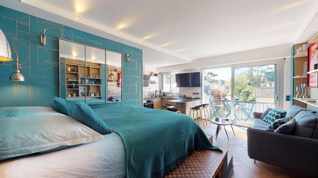 Cet appartement comprend une chambre dotée d'un mur bleu avec un lit et une cuisine. dans l'établissement Ty Braz 4 pers studio 3 min à pied marché, plage, à La Baule