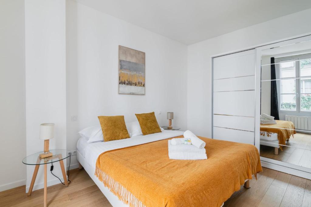 - une chambre blanche avec un grand lit et une couverture orange dans l'établissement 2 pieces renovee a neuf Paris 5 - 4P - FLAT-GUEST, à Paris