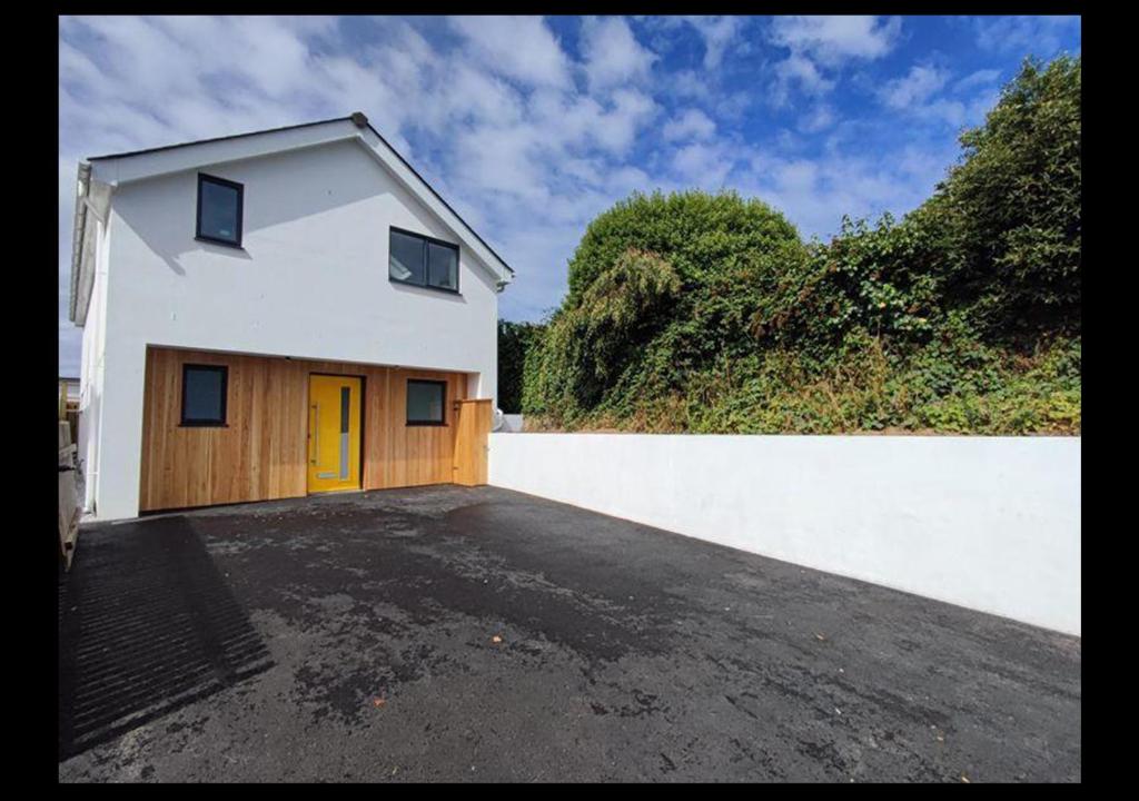 a white house with a yellow door in a parking lot at 3 bed House in Newquay, Cornwall in Newquay