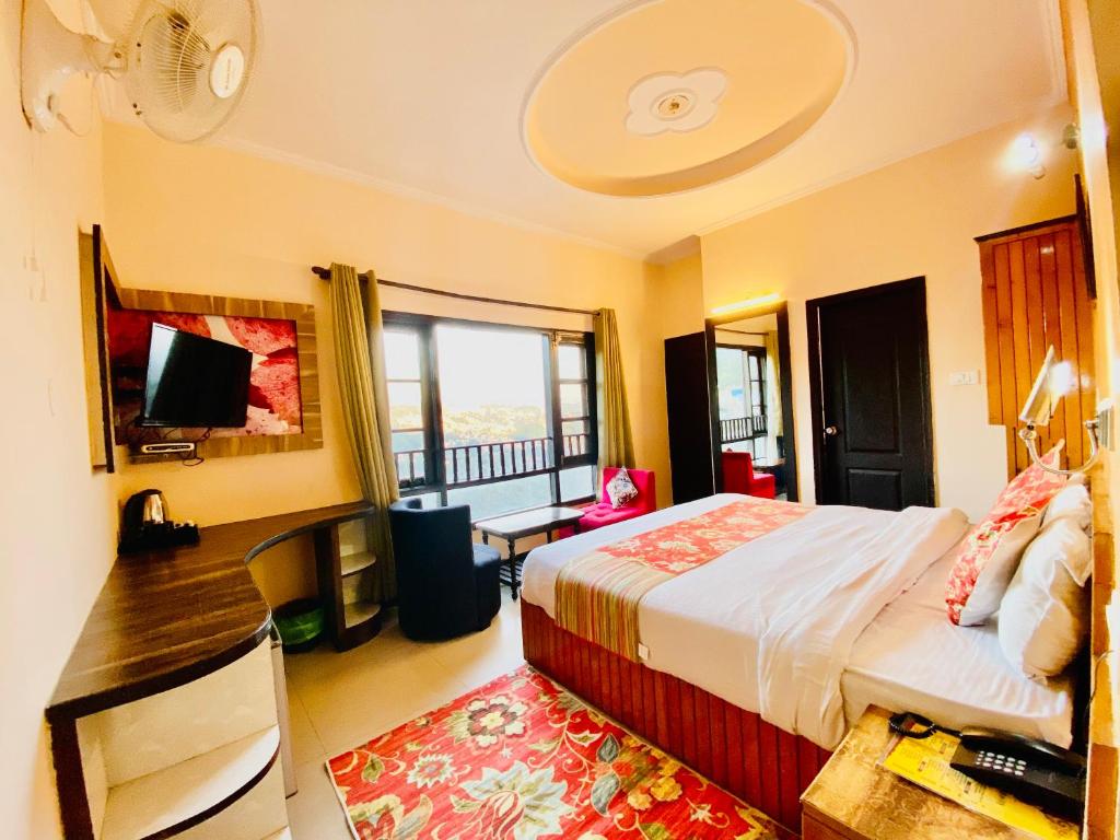 Schlafzimmer mit einem Bett, einem Schreibtisch und einem Fenster in der Unterkunft Hotel De Regency in Pelling