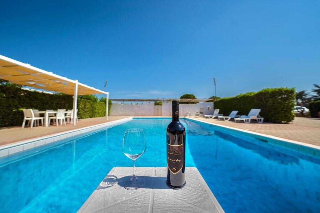 - une bouteille de vin assise sur une table à côté de la piscine dans l'établissement Villa Giada, à Francavilla Fontana