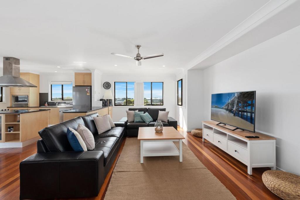 a living room with a black leather couch and a table at Jetty Escape Townhouse in Coffs Harbour